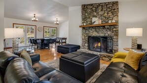A living room with a stone fireplace, leather sofas, and a dining area with a table and chairs.