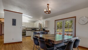 A modern kitchen with white cabinets, a large island with bar stools, and a chandelier.