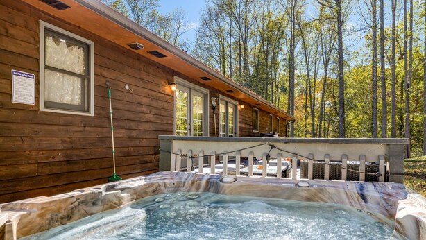 A wooden cabin with a hot tub and a deck.