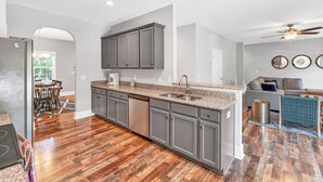 A spacious kitchen with grey cabinets, a stainless steel dishwasher, and a granite countertop.