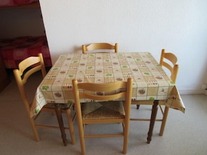 A dining table with a patterned tablecloth, surrounded by four wooden chairs.