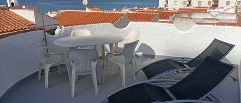A rooftop terrace with a table and chairs, overlooking a coastal cityscape.