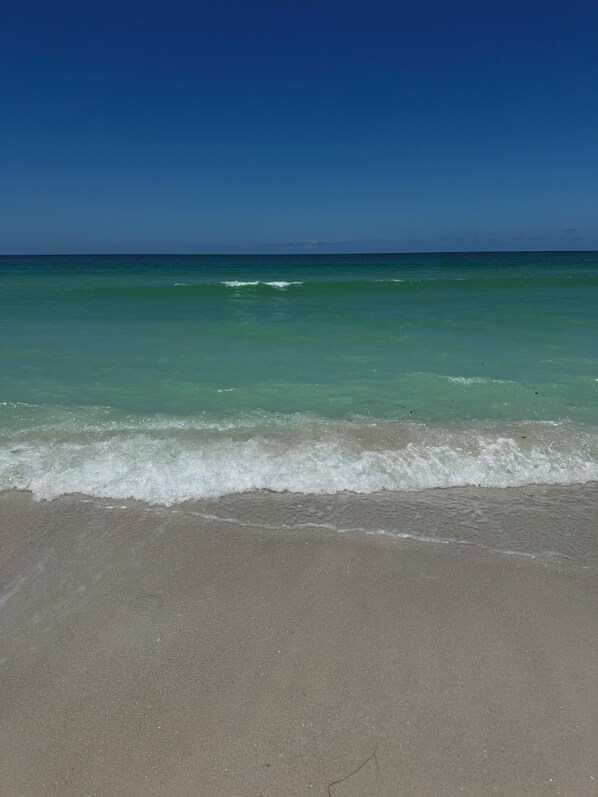 A beach with clear turquoise water and gentle waves.