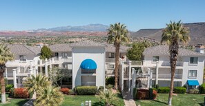 A residential building with multiple balconies, a blue circular window, and a view of mountains in the background.