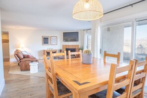 Ein Essbereich mit einem Holztisch und Stühlen, einer Kakteen-Mittelstück und einem Fernseher im Hintergrund.