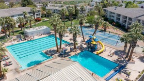 A swimming pool area with multiple pools, palm trees, and a water slide.