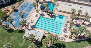An aerial view of a resort with a large swimming pool, tennis courts, and palm trees. - Waterpark resort with basketball, pickleball court (St. George)