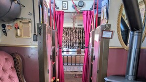 Un interior acogedor con un sillón rosa mullido, una alfombra estampada y un estufa de leña.