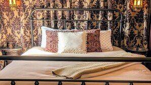 Una cama con estructura metálica, cubrecama estampado y almohadas decorativas.