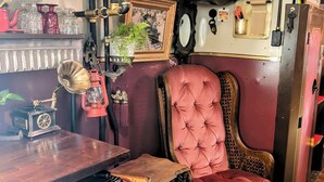 Una habitación de estilo vintage con una butaca rosa tapizada, un escritorio de madera y una radio antigua.