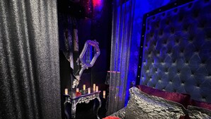 A room with a tufted headboard, a red pillow, and a decorative mirror with candles. - Priamos Hotel Erato (Athens)