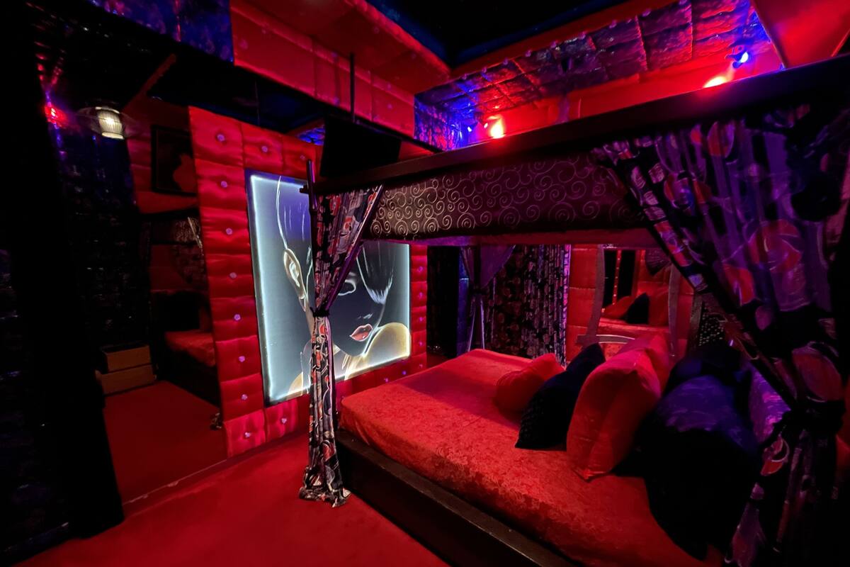 A room with a red carpet, a sofa with red cushions, a patterned curtain, and a wall with a large mirror.