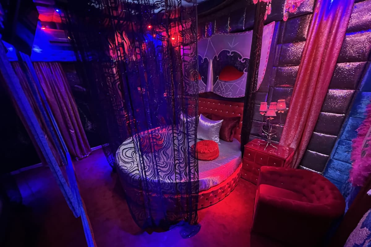 A room with a bed, a red chair, and a decorative canopy.