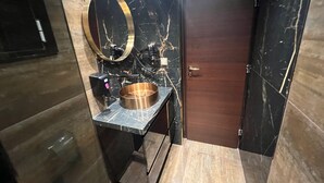 A modern bathroom with a copper sink, a large mirror, and a wooden door. - Priamos Hotel Erato (Athens)