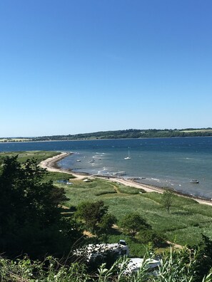 A coastal landscape with a clear view of the sea, boats, and a sandy beach.