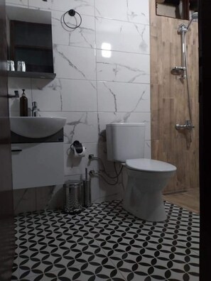 Ein Badezimmer mit Marmorfliesenspiegel, Waschbecken, Toilette und Dusche.