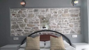 Ein Schlafzimmer mit Steinwand-Bettvorleger, zwei Nachttischen und zwei Kissen.