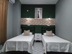 Ein Zimmer mit zwei Betten, einer Ziegelwand als Blickfang und einem Spiegel über den Betten.