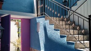 Eine Treppe mit schwarzer Handläufe und gemusterten Wänden, die zu einem Landeplatz mit einer Tür und Topfpflanzen führt.