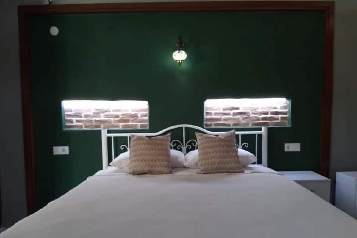 Un lit avec une tête de lit blanche et deux fenêtres décorées de motifs en briques.