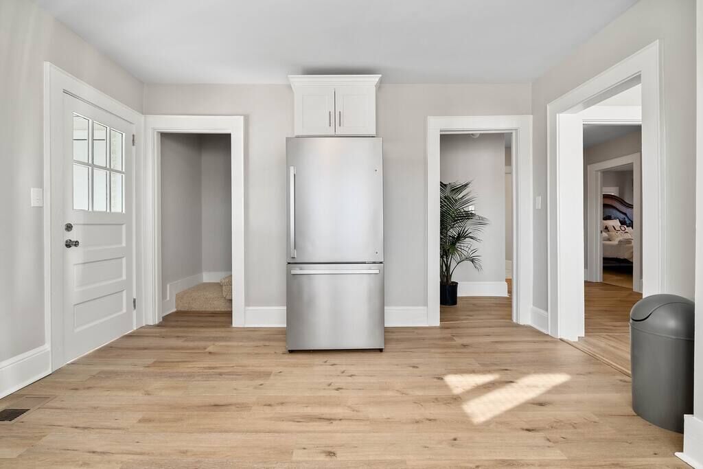 Eine geräumige Küche mit einem Edelstahlkühlschrank, Holzböden und weißen Wänden.