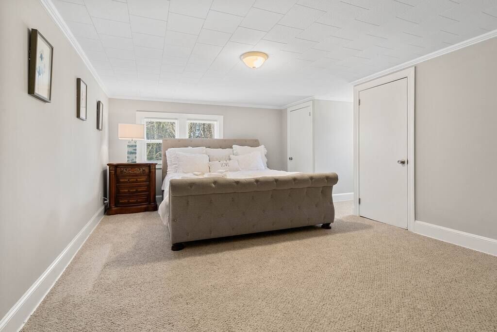 Een slaapkamer met een groot bed, een dressoir, een raam en een deur.