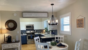 A kitchen with a dining area, featuring a clock, a coffee station, and a sign that says "LET THE SEA set you free." - Beachside Daytona Beach Shores 5 min walk to beach, restaurants and more! (Port Orange)
