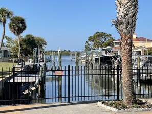 A marina with boats docked, a "KEEP OFF FENCE" sign, and a clear sky.