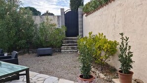 A patio area with a stone table, potted plants, and a seating area. - Comfortable air-conditioned studio in a quiet villa 15 km from Cannes (Peymeinade)