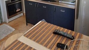 A kitchen with a television, a clock, and a refrigerator. - Comfortable air-conditioned studio in a quiet villa 15 km from Cannes (Peymeinade)