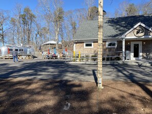 A campground with RVs, picnic tables, and a building with a 'Welcome' sign. - Coastal Cape Hideaway - Outdoor Shower & Fire-pit! (Mashpee)