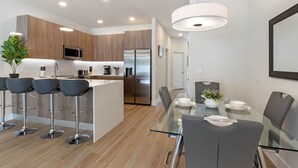 Una cocina moderna con una isla central, electrodomésticos de acero inoxidable y taburetes de bar.
