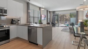 A modern kitchen with built-in appliances, a central island, and a dining area with a glass table and chairs. - Jose's Tikki Room near Disney (Clermont)