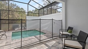 A covered outdoor pool area with a glass enclosure, seating, and a small table with a plant. - Jose's Tikki Room near Disney (Clermont)