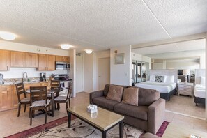 A compact living space with a kitchenette, a dining area, a sofa, and a bedroom.