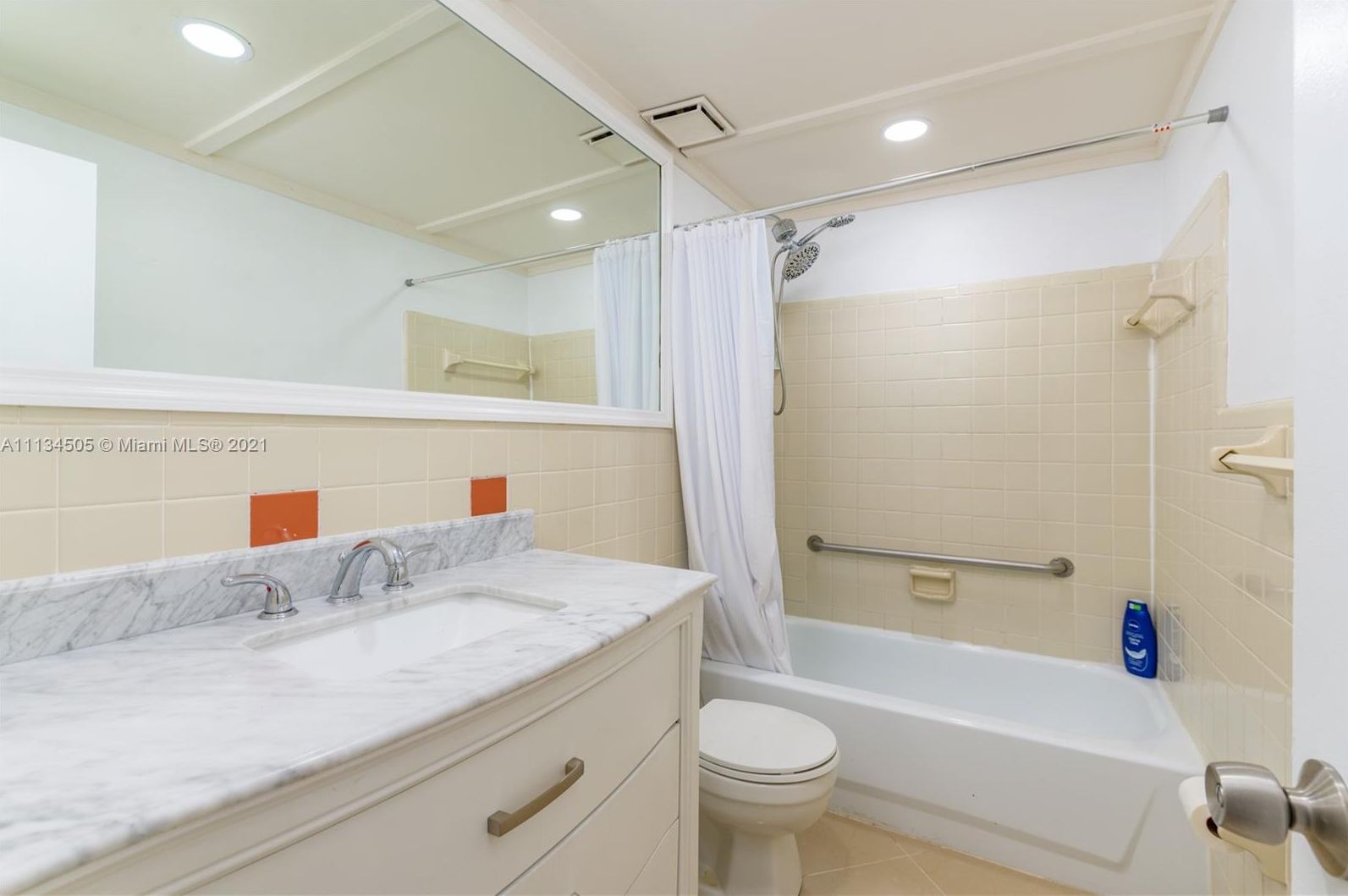 A bathroom with a marble sink, a toilet, a bathtub, and a shower with a curtain.