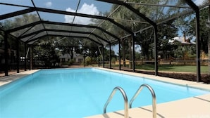 A covered swimming pool with a metal frame and glass panels, surrounded by trees and a fenced yard. - University House - 8 Bedrooms - Walk to UF / Stadium (Gainesville)