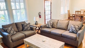 A living room with two sofas, a coffee table, and a dining table with chairs. - University House - 8 Bedrooms - Walk to UF / Stadium (Gainesville)