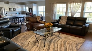 A modern living room with leather sofas, a glass coffee table, and a patterned rug.