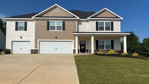 A two-story house with a front porch, two garages, and a well-maintained lawn.