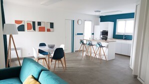 A modern living room with a sofa, dining area, and kitchen.