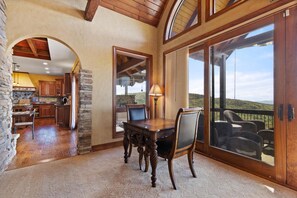 A spacious dining area with a wooden table and chairs, a stone fireplace, and a view of the outdoors through large sliding glass doors.
