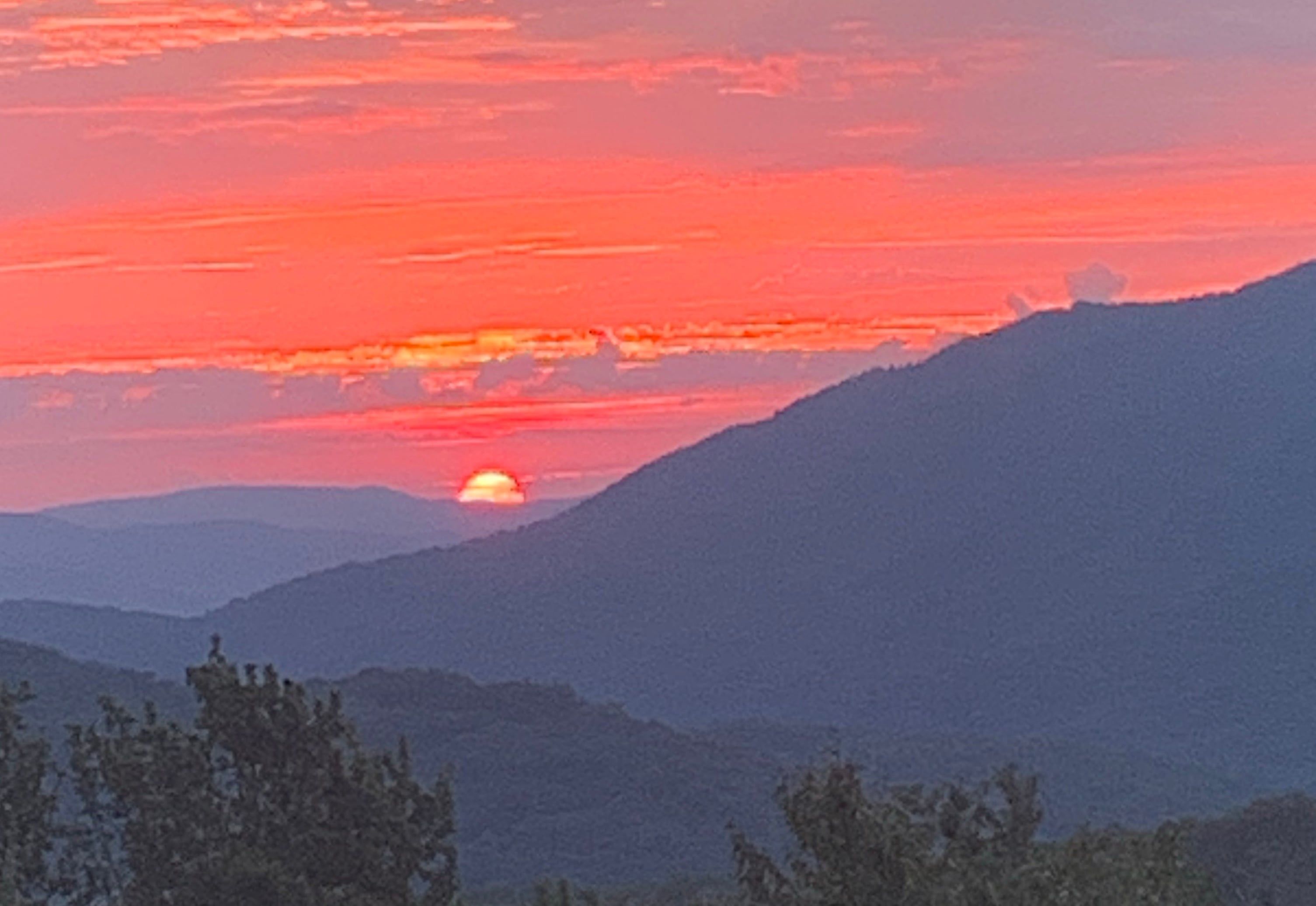 A sunset over a mountainous landscape with a visible sun.