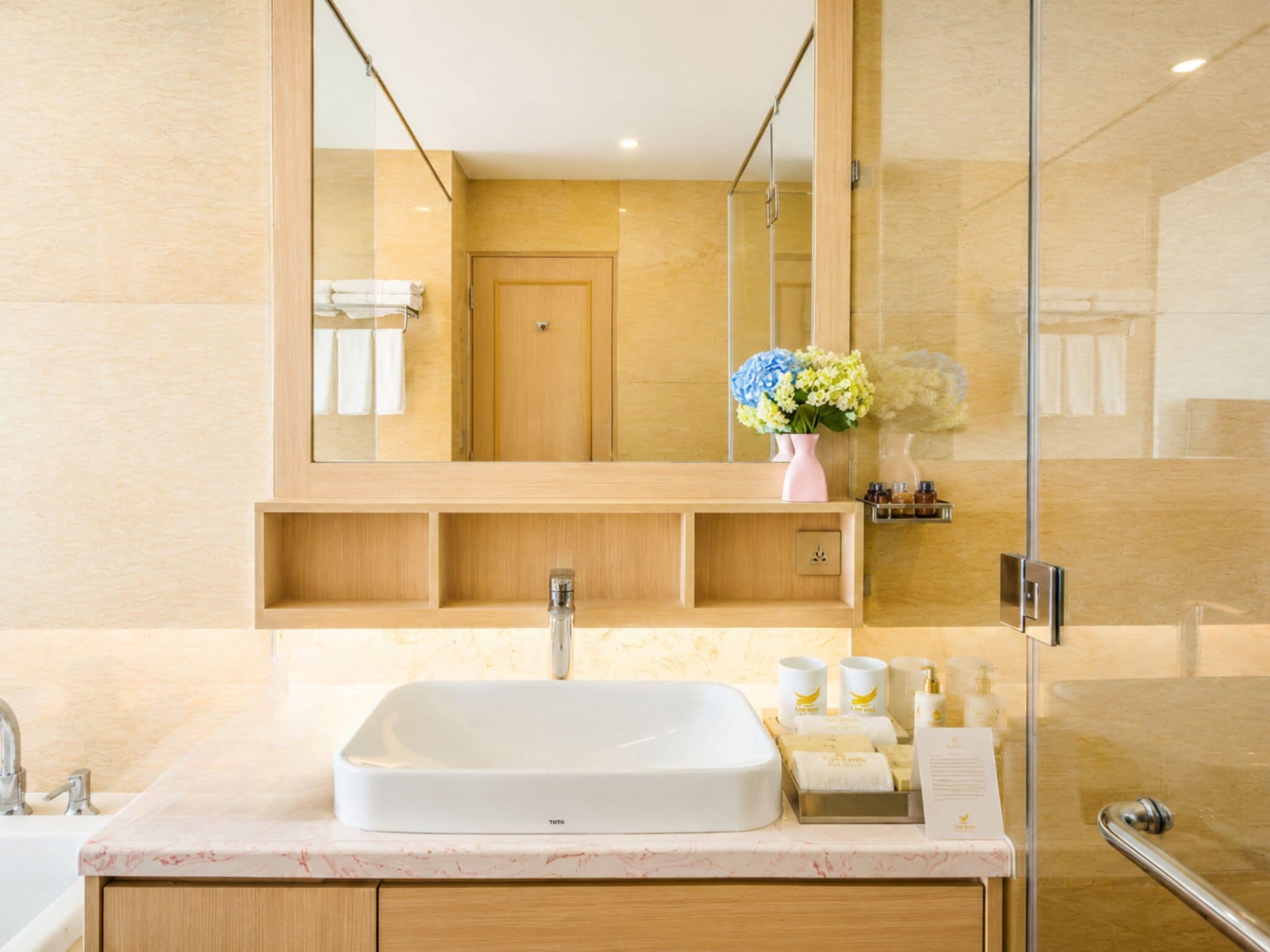 A modern bathroom with a large mirror, a white sink, and a shower area.