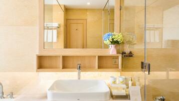 A modern bathroom with a large mirror, a white sink, and a shower area.
