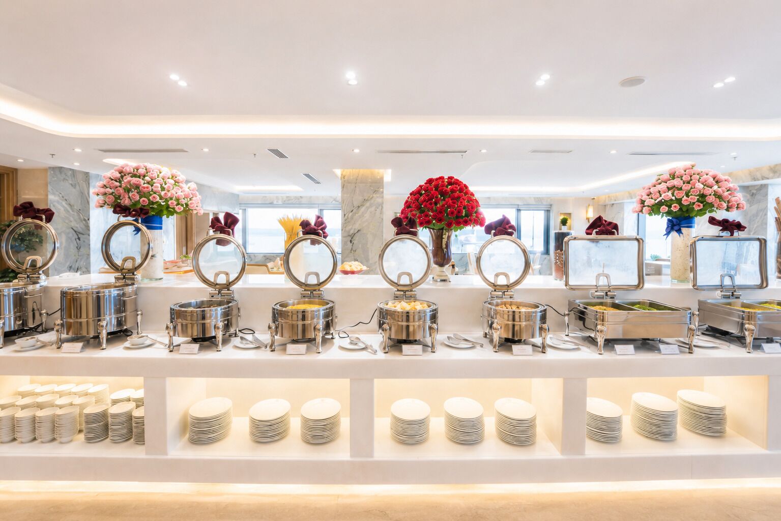 A buffet setup with multiple food stations, round mirrors, and flower arrangements.