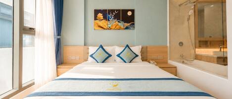 A hotel room with a bed, a nightstand, a painting on the wall, and a bathroom with a shower.