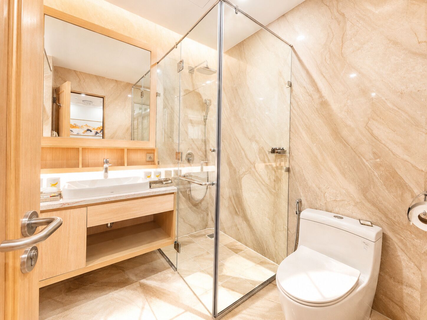 A modern bathroom with a glass shower enclosure, a white toilet, and a vanity with a mirror.