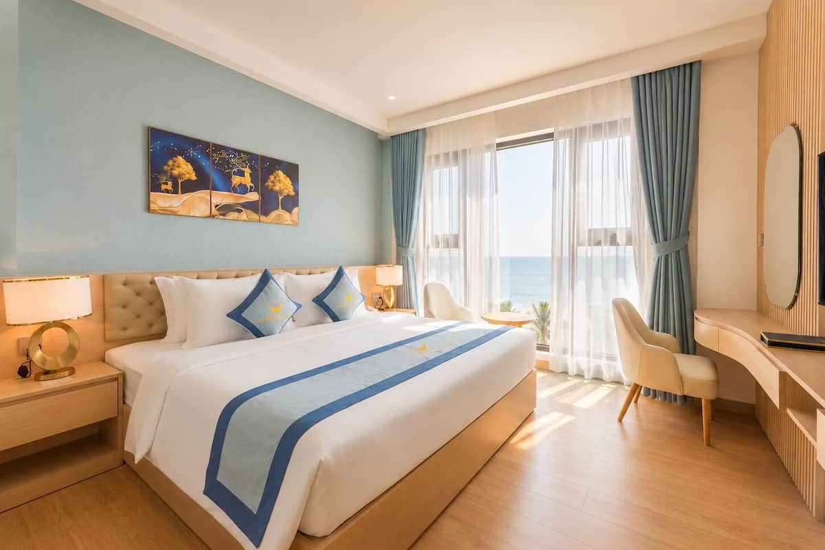 Una habitación de hotel con cama, escritorio, silla y un cuadro en la pared.