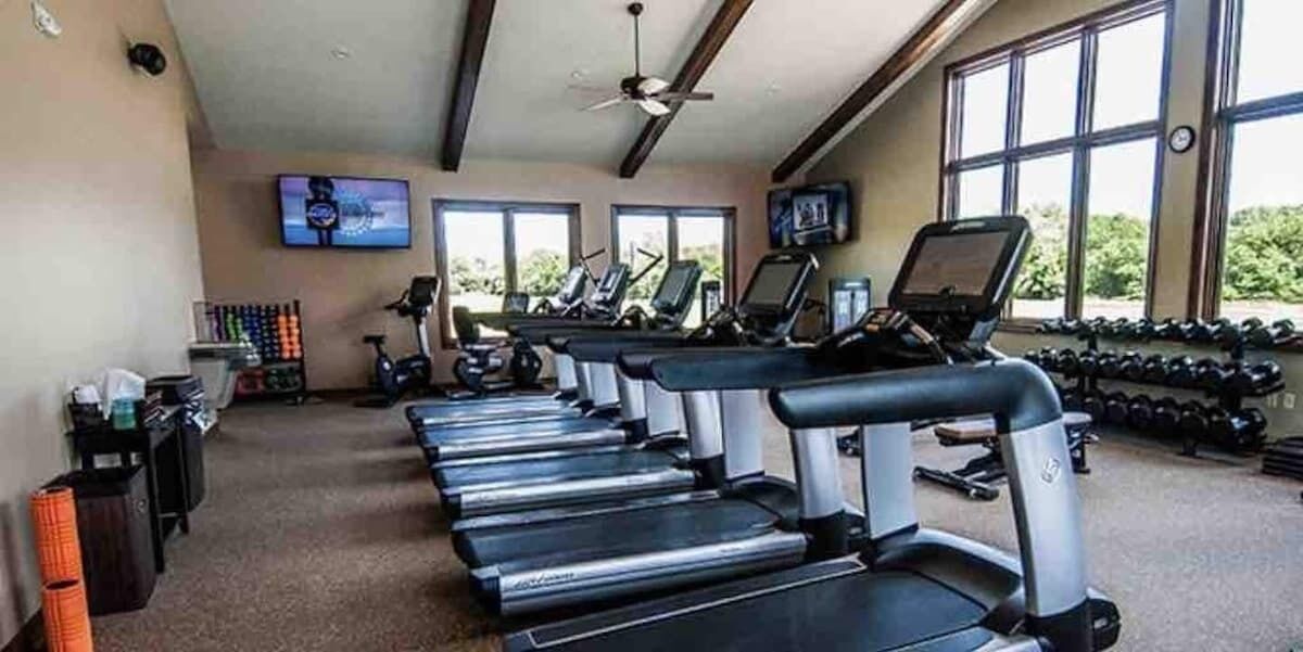 Une salle de sport équipée de tapis de course, de vélos d’exercice et d’haltères.